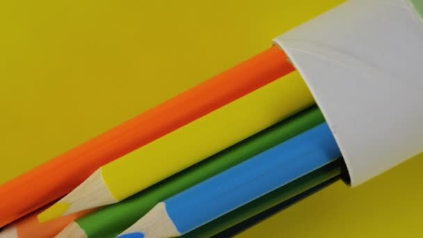 Buntstifte in einer Röhre auf gelbem Hintergrund. 4K - Filmmaterial, Video