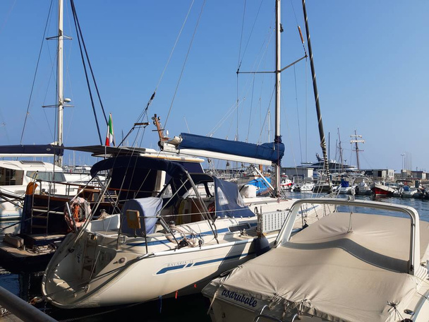 リグーリア州,イタリア- 2021年6月17日:リグーリア州の海辺を旅する。海辺と古い村へのパノラマビュー。夏の日にいくつかのボートで港への美しい景色 - 写真・画像