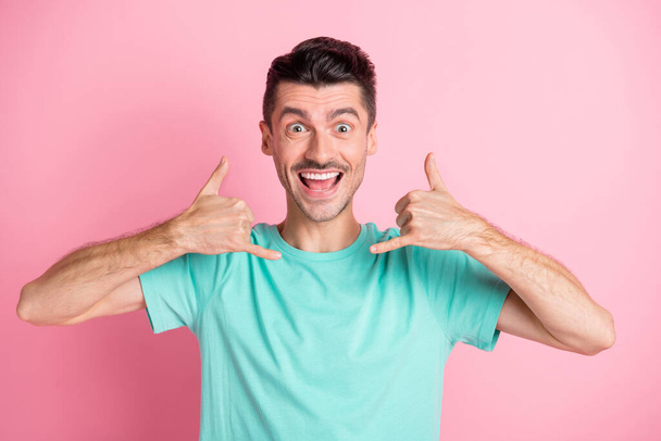 Photo of young handsome man happy positive smile gesture fingers call me sign isolated over pink color background - Foto, Imagem