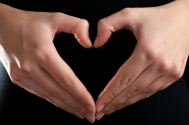 ανθρώπινα χέρια τη καθιστώντας την καρδιά σε μαύρο φόντο - Φωτογραφία, εικόνα
