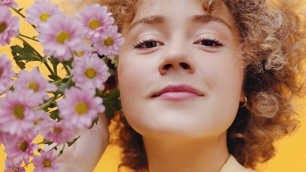 mooi meisje Holding paars gerbera madeliefjes dicht bij haar gezicht - lente - Foto, afbeelding