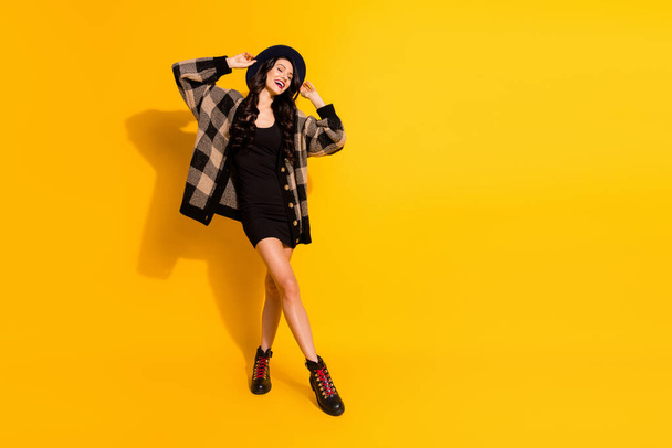 Full body photo of joyful relaxed young woman enjoy weekend wear black boots isolated on yellow color background - Foto, Imagen