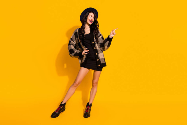 Photo of lady direct finger up look empty space wear hat plaid coat short dress boots isolated yellow color background - Fotoğraf, Görsel