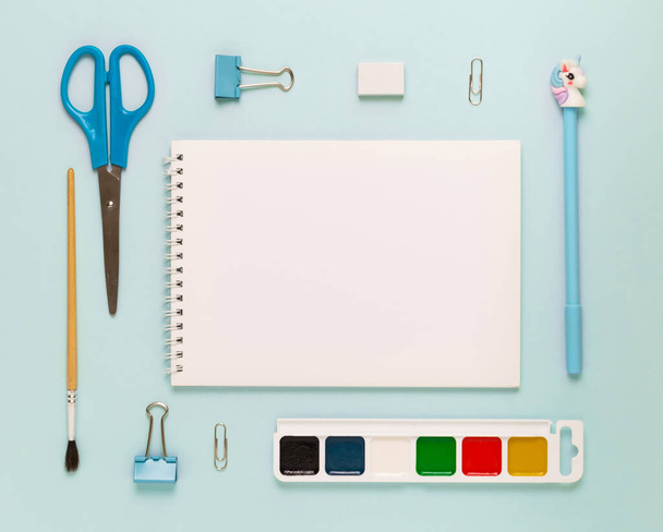 Top view of modern white blue office desktop with school supplies and stationery on table around empty space for text. Back to school concept flat lay with mockup - Φωτογραφία, εικόνα