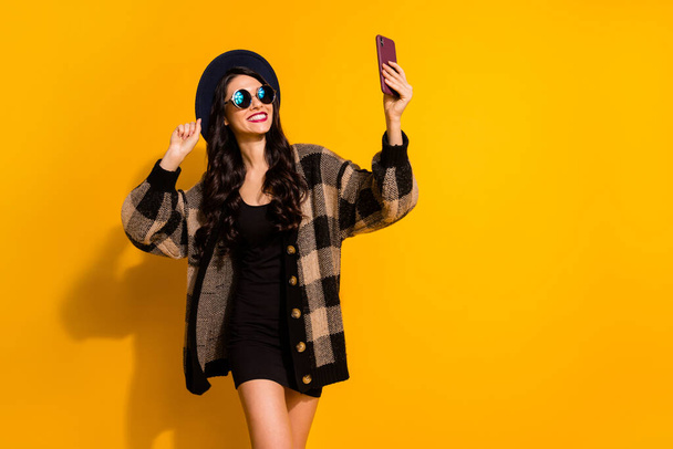 Photo of stunning cheerful brunette lady hold phone take selfie good mood isolated on yellow color background - Zdjęcie, obraz