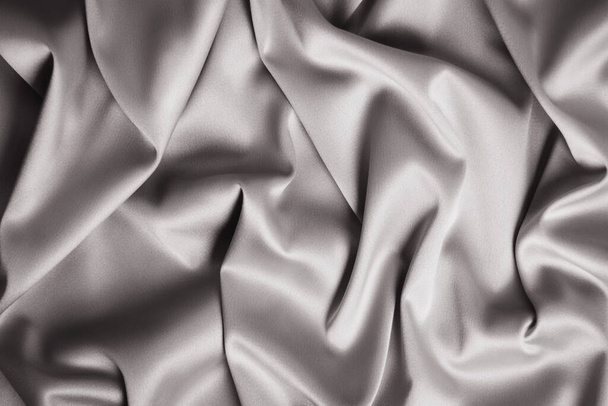 Textured backdrop of gray silk or satin. Shiny waves of textiles. Copy space - Φωτογραφία, εικόνα