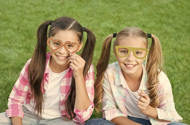 Summer party. Happy children hold prop glasses. Party photobooth. Party girls celebrate on green grass. Party look. Fun and entertainment. Carnival fashion accessories. Fancy beauty - 写真・画像