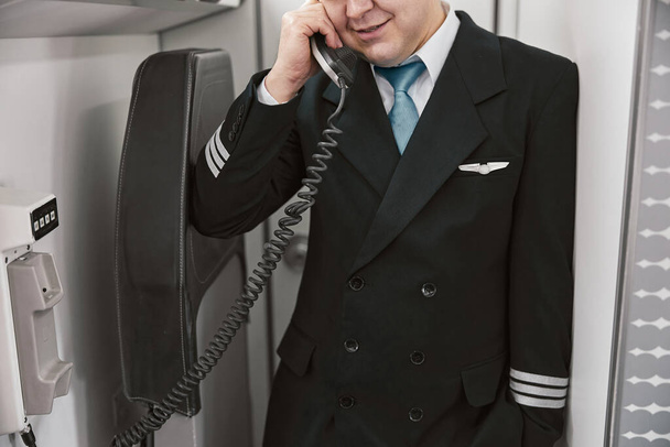 Male pilot talk on board phone in airplane - Photo, Image
