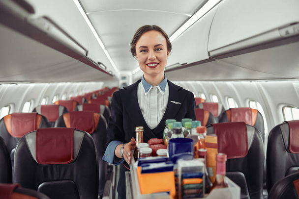 Stewardess carrying food trolley in airplane cabin - Φωτογραφία, εικόνα