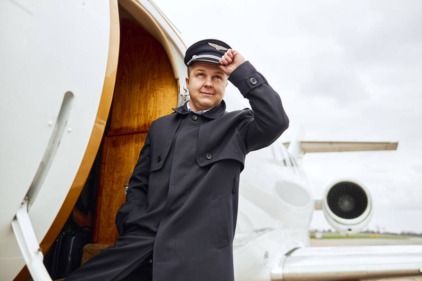 Pilot standing near entrance to airplane jet - Foto, Imagen