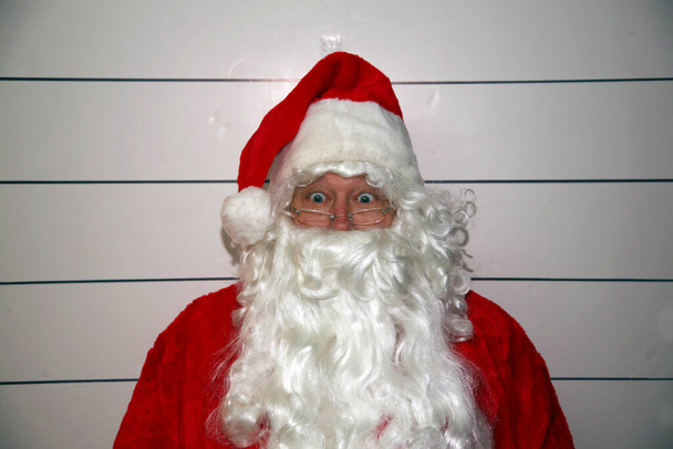 Kerstman mok neergeschoten. Kerstman mok neergeschoten. De Kerstman is gearresteerd en zijn foto is genomen. De kerstman gearresteerd met Kerstmis. De Kerstman heeft zijn mok schot. De Kerstman is bang. De kerstman gearresteerd met Kerstmis. Santa politiefoto op het politiebureau. - Foto, afbeelding