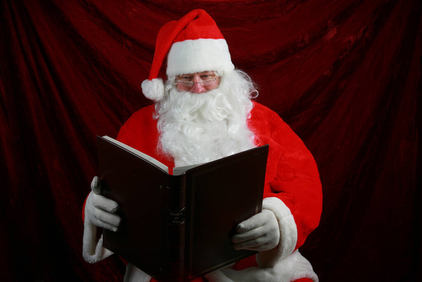 Zlobivé nebo hezké. Santa Claus čte ze své velké knihy o tom, kdo byl nezbedný nebo Nice letos před Vánocemi. Santa Claus drží svou Zlobivou a pěknou knihu. Santa Claus si dělá poznámky o tom, kdo byl zlobivý nebo hodný. Santa říká, být milý.  - Fotografie, Obrázek