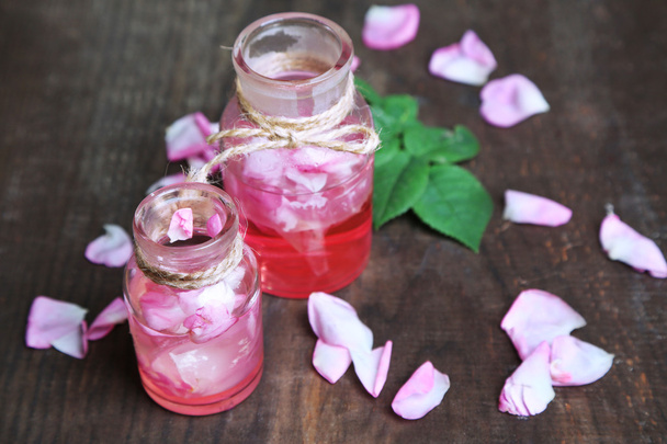 Rose oil in bottles on color wooden background - Foto, afbeelding