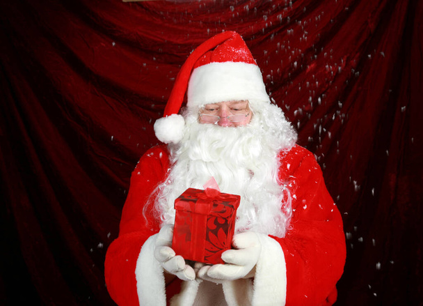 Santa Claus Navidad. Santa Claus está emocionado por lo que ve en un regalo de Navidad de terciopelo rojo dado a él por sus elfos como un regalo de Navidad para él. Santa Claus tiene un regalo de Navidad para ti. Papá Noel en su traje tradicional de terciopelo rojo.  - Foto, Imagen