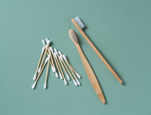 Bambu diş fırçaları ve pamuklu çubuklar pastel yeşil arka planda. Sıfır atık kavramı. Yukarıdan görüntüle. - Fotoğraf, Görsel
