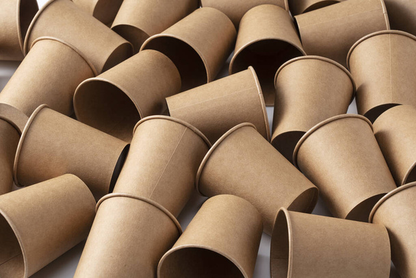 Una gran cantidad de vasos de papel reciclado marrón sobre un fondo blanco. El concepto de cero residuos. - Foto, Imagen