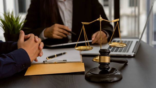 Consulting of business women and male lawyers or judges counselors. Legal services concept with judge's hammer and golden scales with laptop on table. - Photo, Image