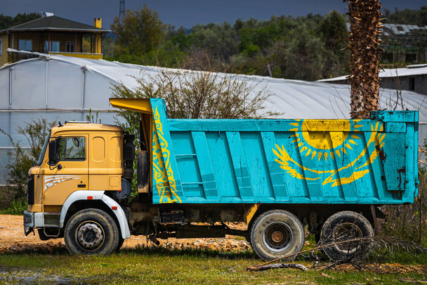 Dump truck con l'immagine della bandiera nazionale del Kazakistan è parcheggiata sullo sfondo della campagna. Il concetto di esportazione-importazione, trasporto, consegna nazionale delle merci - Foto, immagini