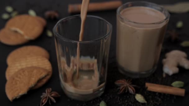 Dvě sušenky a čaj podávané v průhledném skle k ranní snídani. Populární indické koření hvězda anýz, Dalchini, Elaichi, a Adrak drželi pohromadě na podložce na rozmazaném pozadí  - Záběry, video