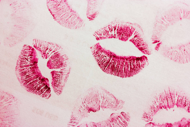 Abstract pink kisses isolated on white background. Lots of female lip prints on paper. Beautiful lips stamps isolated. Valentine's day, romantic mood and love concept. Lipstick kisses. Print of lips.  - Photo, Image