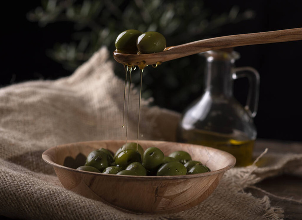 A closeup shot of a person holding a spoon of fresh green olives - Foto, Imagem