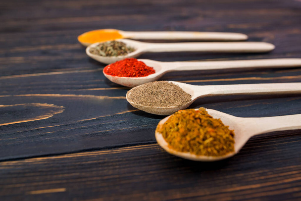 different spices in wooden spoons on a wooden background. - Φωτογραφία, εικόνα