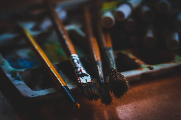 A closeup shot of paintbrushes and watercolors in a table background - Φωτογραφία, εικόνα
