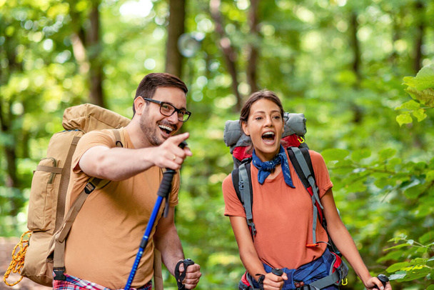 Active young couple hiking in forest with backpacks,enjoying in new adventure. - Фото, зображення
