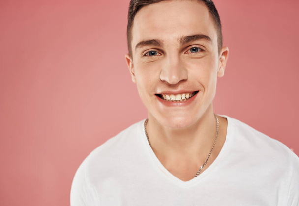 sonriente hombre primer plano blanco camiseta rosa fondo - Foto, Imagen