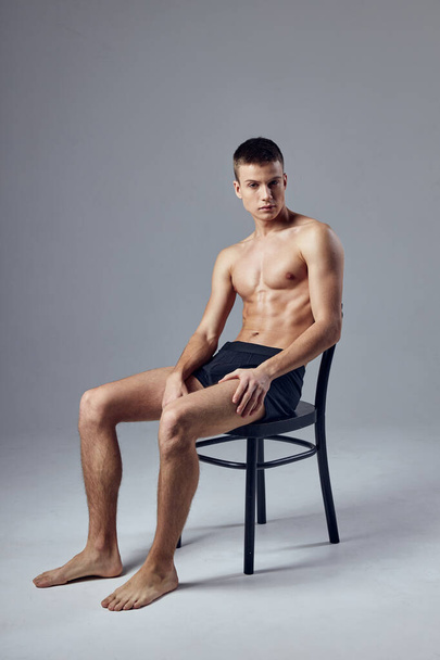 sporty man in black shorts sitting on a chair gymnastics hall rest - Photo, Image