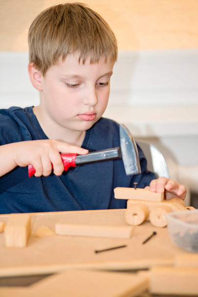 Niño jugando con juguetes de bricolaje carpintería construcción herramienta taller kit. Expresión facial artística.  - Foto, Imagen