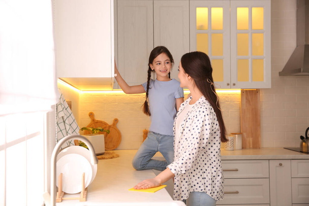 Mother and daughter cleaning up kitchen together at home - Foto, imagen