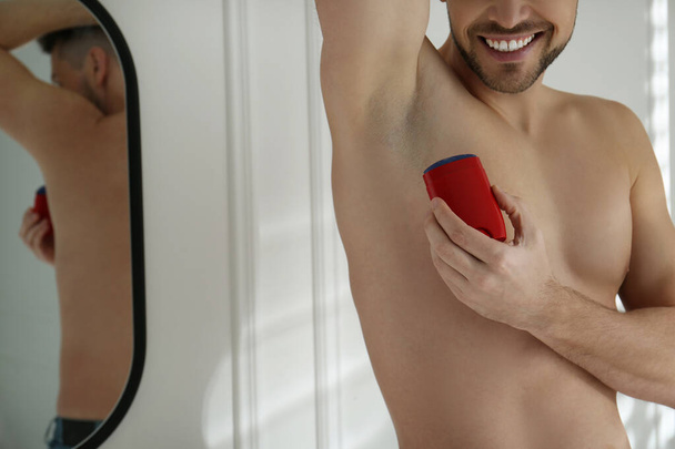 Man applying deodorant in bathroom, closeup. Space for text - 写真・画像