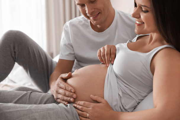 Young pregnant woman with her husband indoors, closeup - Fotó, kép
