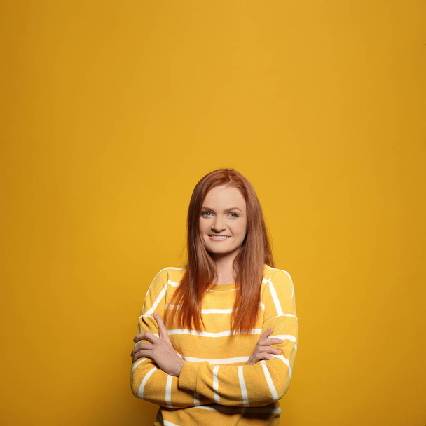 Candid portrait of happy young woman with charming smile and gorgeous red hair on yellow background - Fotoğraf, Görsel