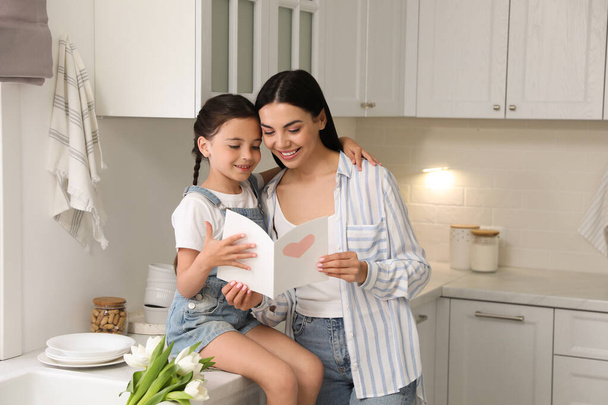 Little daughter congratulating her mom in kitchen at home. Happy Mother's Day - Foto, imagen