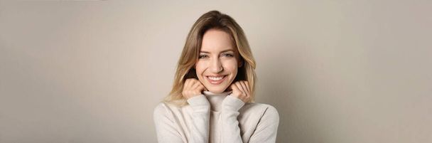 Portrait of happy young woman with beautiful blonde hair and charming smile on beige background. Horizontal banner design - Фото, изображение