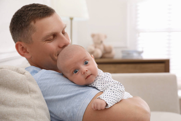 Mutlu bir baba kucağında küçük bebeğiyle evde, mesaj atmak için yer arıyor. - Fotoğraf, Görsel