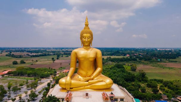 aerial front view of big ancient golden mediated buddha at Wat Muang Temple, Ang Thong province, Thailand, drone high angle top view - Valokuva, kuva