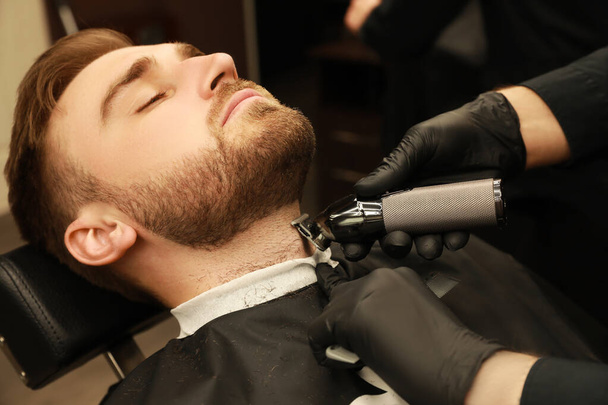 Professional hairdresser working with client in barbershop - Fotó, kép