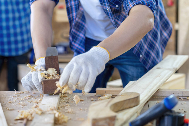 Un carpintero está usando un sacapuntas. Carpintero constructor maneja un plano de tablón de madera en el taller. - Foto, imagen