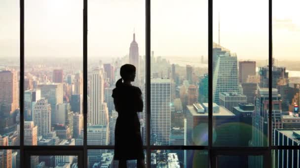 Kobieta z sylwetką wyglądająca przez okno biura na Manhattanie - Materiał filmowy, wideo