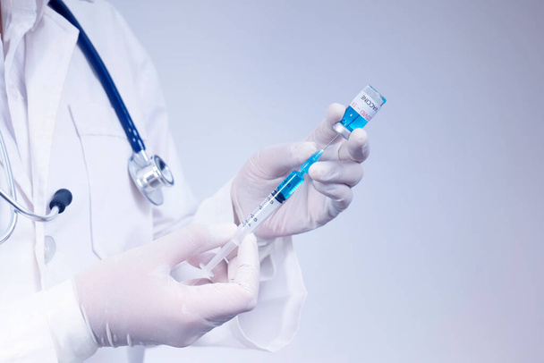 Doctor holds syringe and coronavirus vaccine bottle,concept of corona virus treatment - Фото, изображение