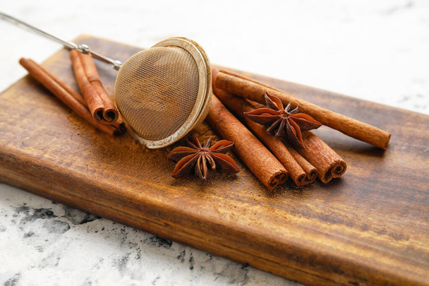 Tea strainer and aromatic cinnamon on table - Fotó, kép