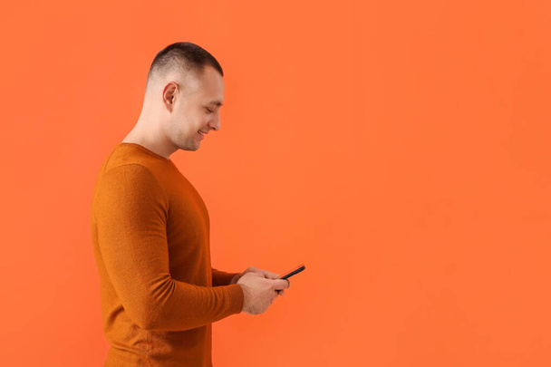 Молодой человек с мобильным телефоном на фоне цвета - Фото, изображение