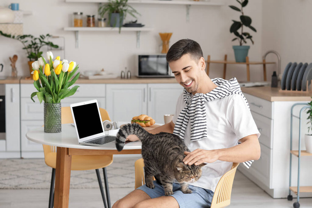 Hombre joven con gato lindo en la cocina - Foto, imagen