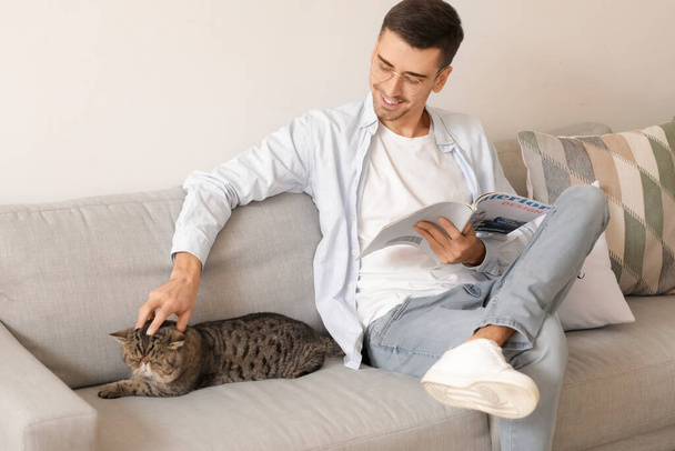 Young man with cute cat at home - Foto, Bild