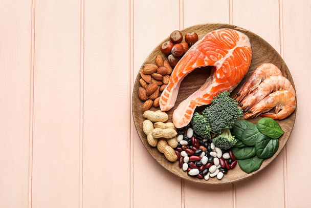 Placa con productos saludables ricos en vitamina E sobre fondo de madera de color - Foto, imagen