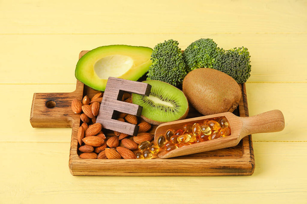 Дошка зі здоровими продуктами, багатими вітаміном E на кольоровому дерев'яному фоні
 - Фото, зображення