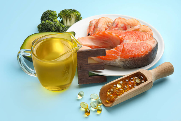 Placa con productos saludables ricos en vitamina E y cápsulas de aceite de pescado sobre fondo de color, primer plano - Foto, imagen